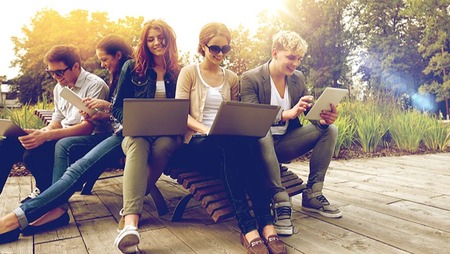 Eine Gruppe Studenten sitzt nebeneinander und arbeitet an Ihren Laptops