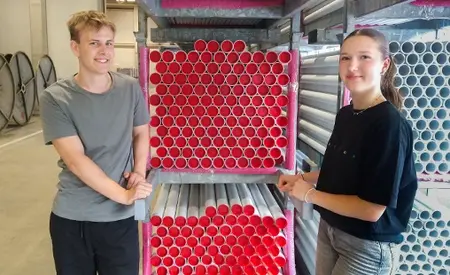 Zwei Gerodur Ferienarbeiter stehen an einer Palette mit Heizungsrohren