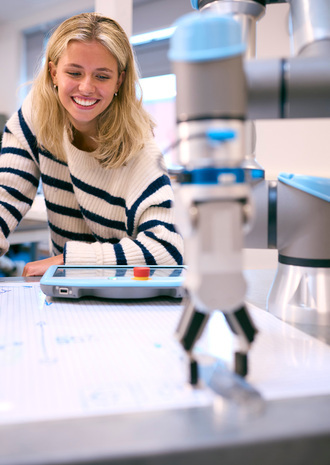 Studentarbeitet an einem Tisch mit Zeichnung und Robotik